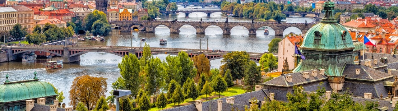 Scenic view of bridges on the Vltava river and of the historical center of Prague: buildings and landmarks of old town with red rooftops and multi-coloured walls.
